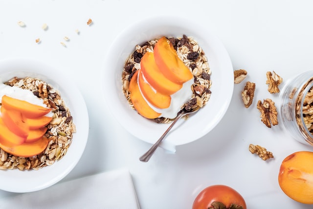 bowl of cereals with sliced fruits and spoon